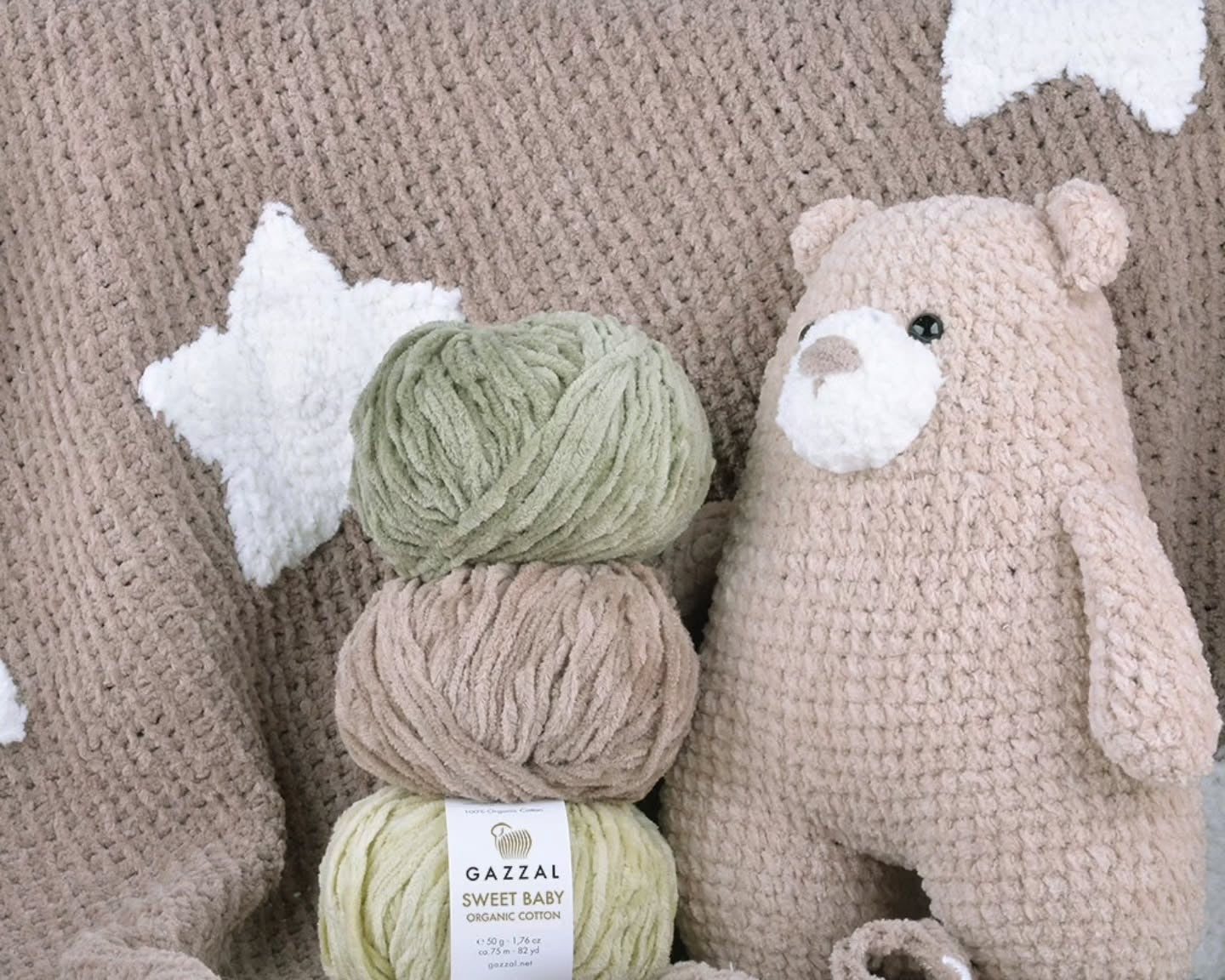 Gazzal Sweet Baby organic cotton chenille yarn balls next to a crocheted plush teddy bear and a star blanket